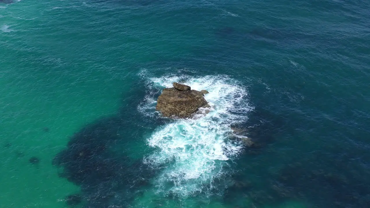 Aerial drone view of waves crashing against a rock in the sea in st ives Cornwall