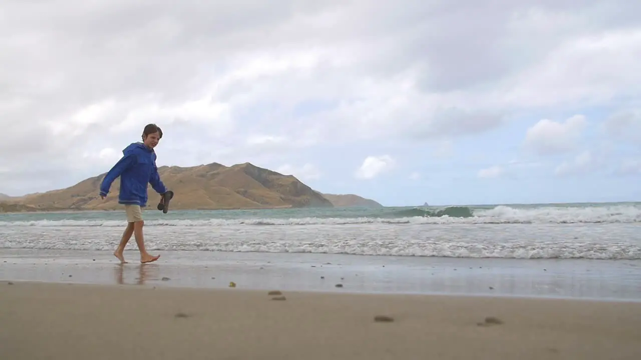 Young Boy Walking Along Windy Beach