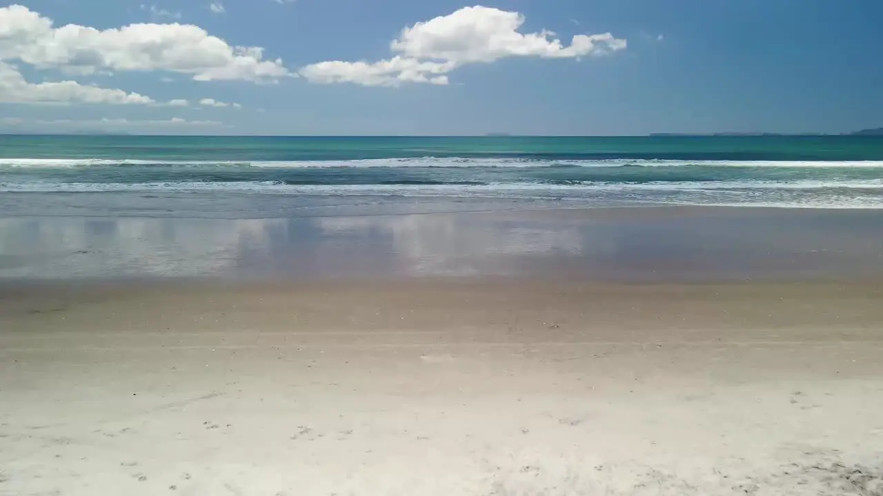 Drone flying onto the white sands of Matarangi beach Coromandel New Zealand