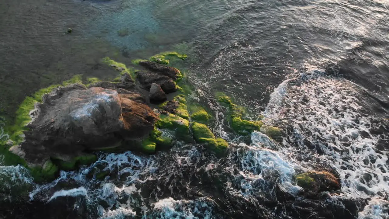 Aerial shot around rock in the sea at sunset