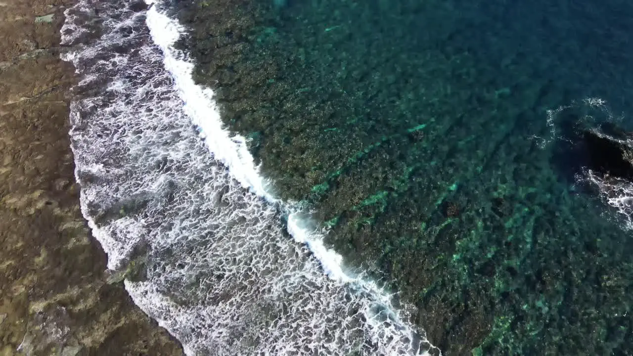 Flying over seashore with waves breaking on uniquely shaped stone reefs