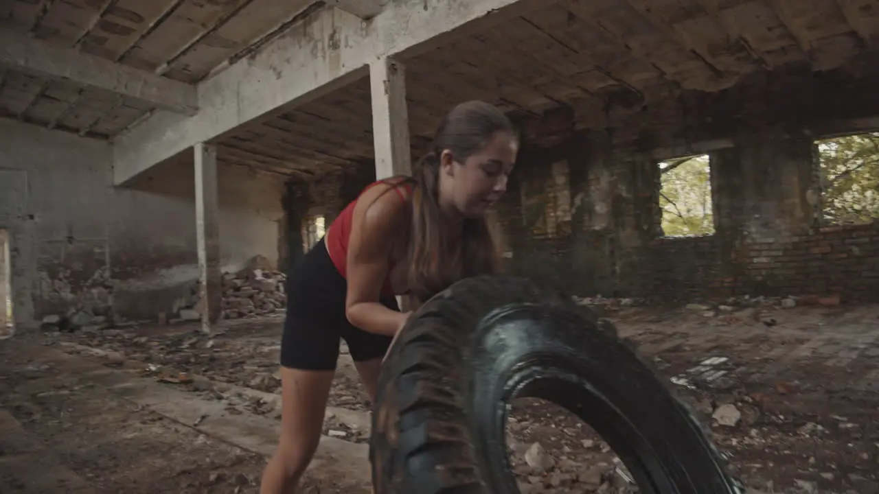 Young woman working out with a big tire