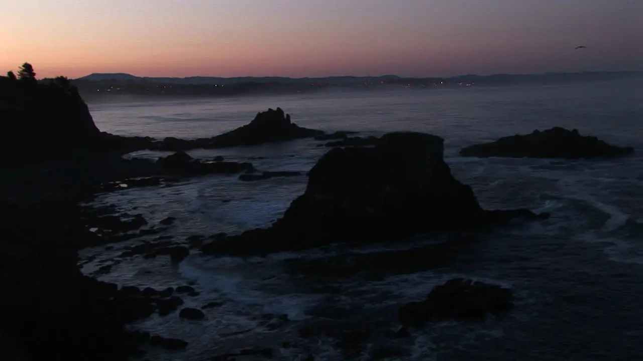 A Broad Band Of Pink And Orange Sky Brightens This Footage Of A Gray Rocky Coastline