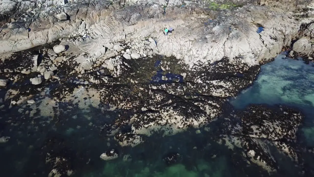 aerial view of a beach made with rocks in Connemara people stand on a cliff