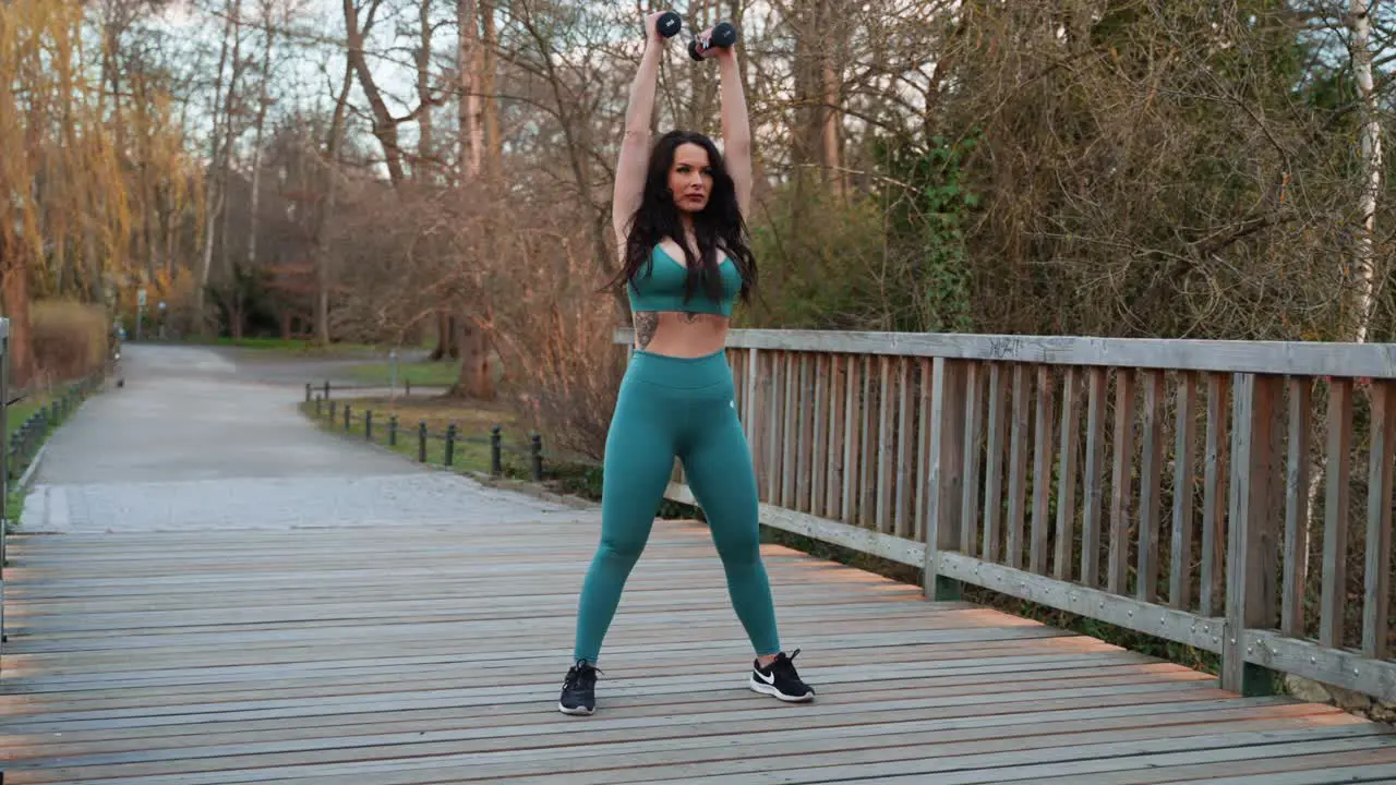 Sporty women lifting weights in a park on the bridge