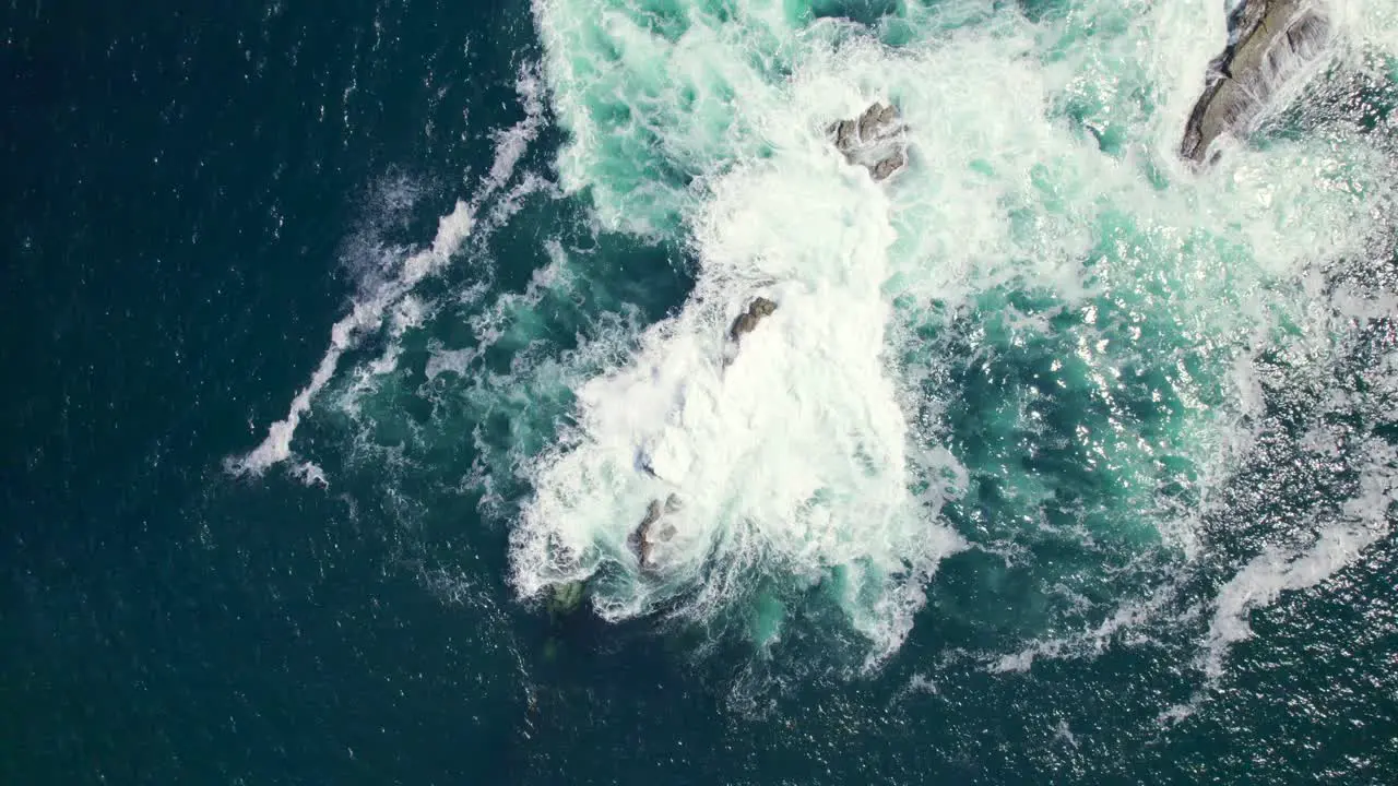 Aerial view of a sea rock with water splashing