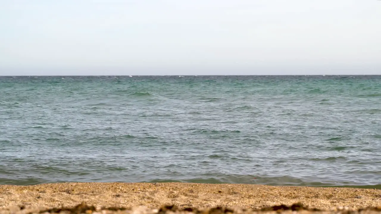 Low angle minimal shot over waves in ocean and sand with sky