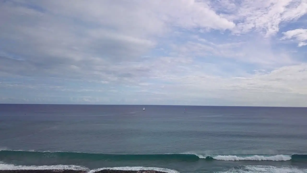 Aerial view of lone sailboat in vast ocean with blue skies and clouds