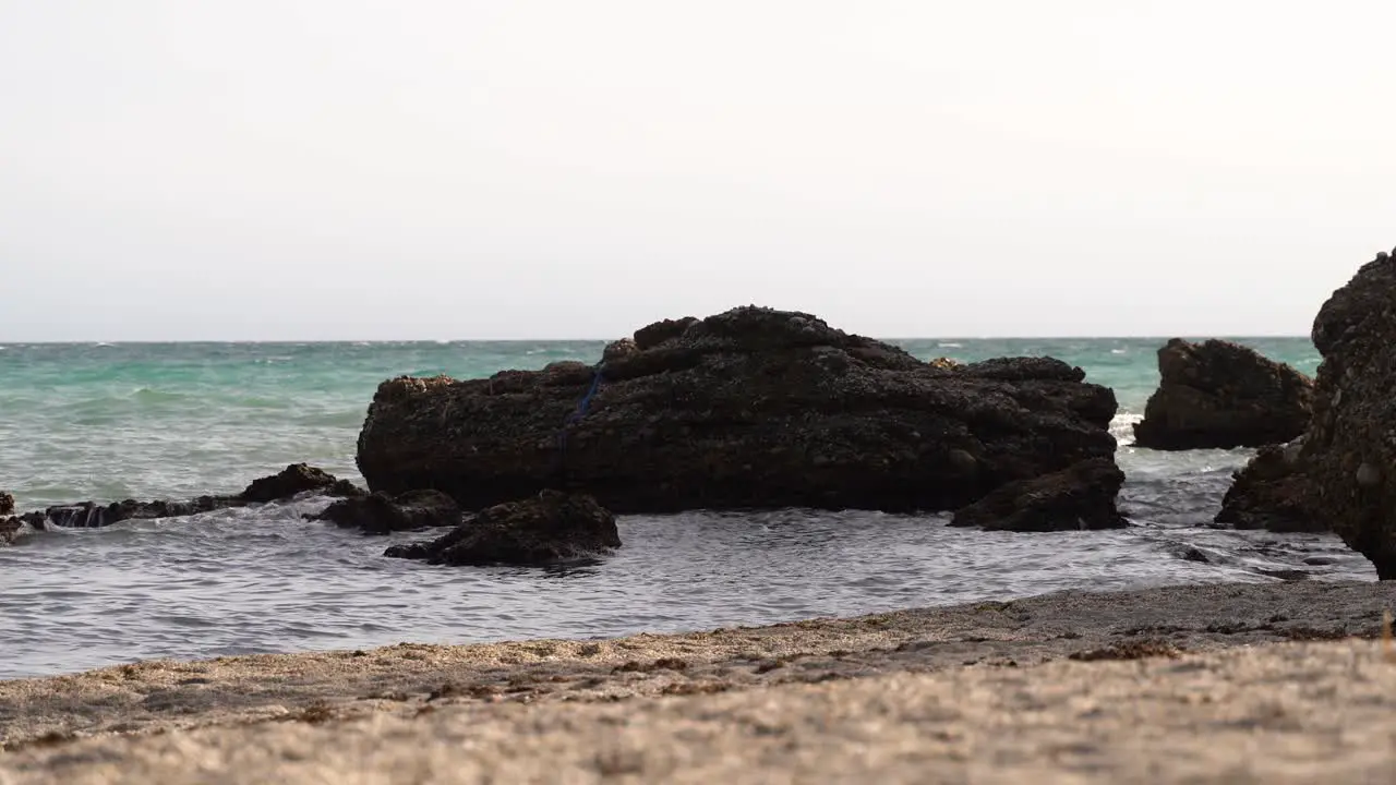 Low angle view over waves breaking against rocks on beach