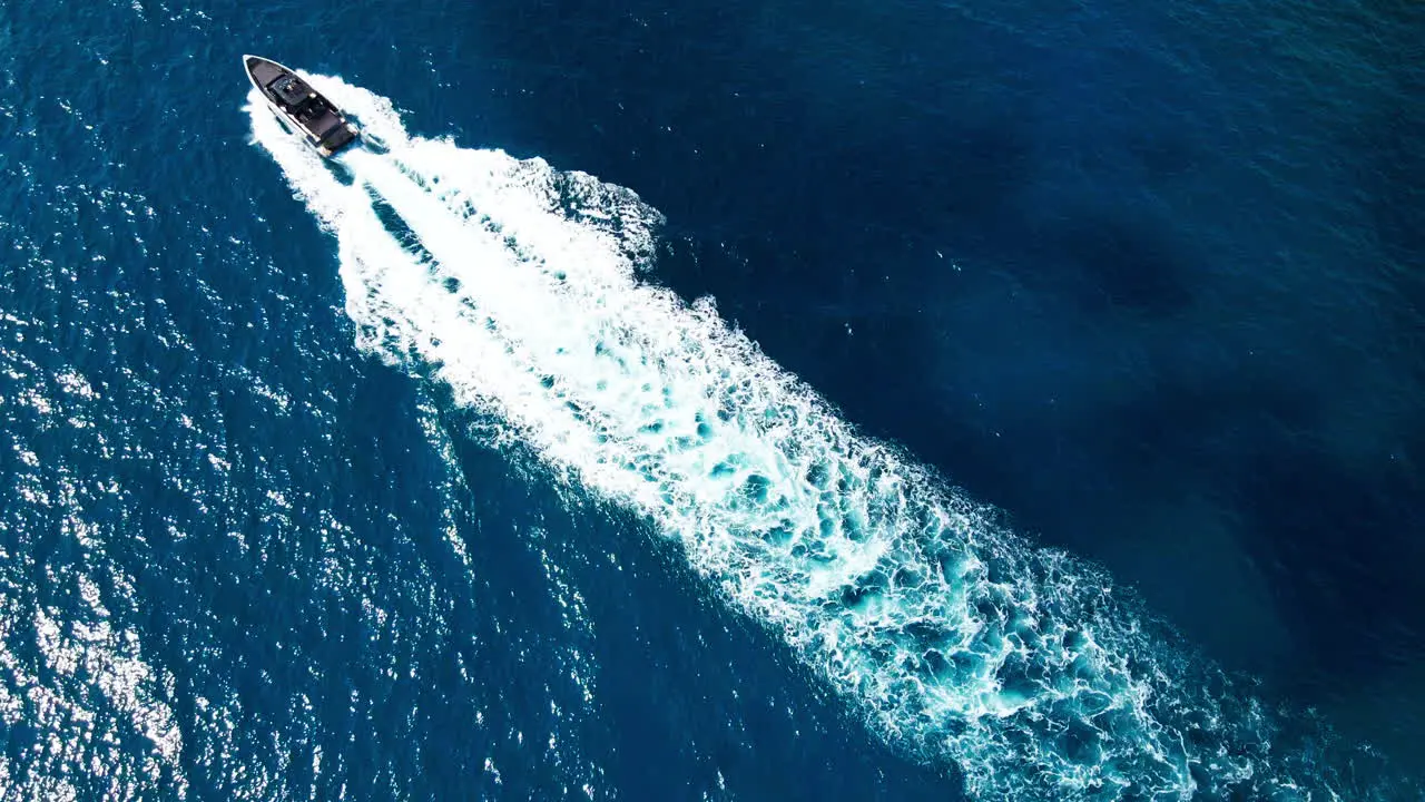 Luxury speedboat travelling across frame in clear glistening Mediterranean Sea in Mallorca aerial top down view