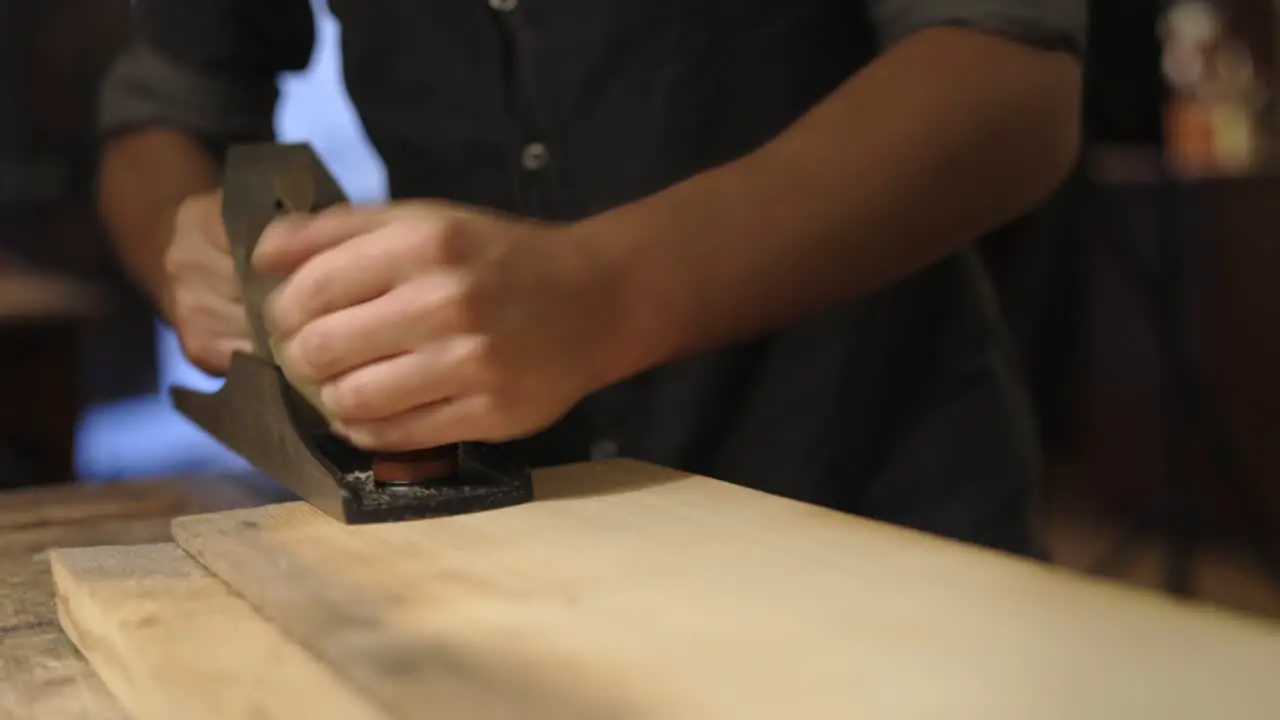 Craftsman planing wooden plank in workshop