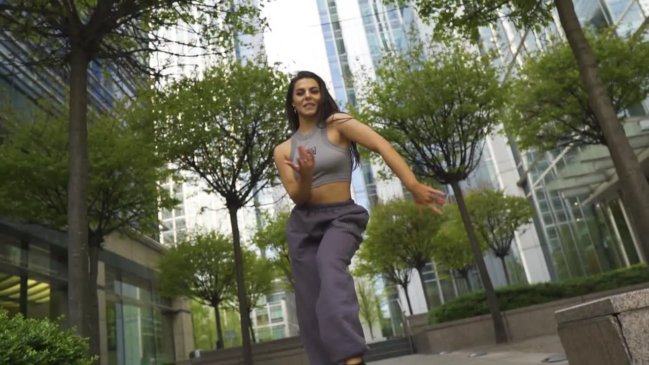 Urban hip hop street dancer with joggers sports bra and trainers is moving her body like a pro various mixture of styles freestyling outdoor on street in city