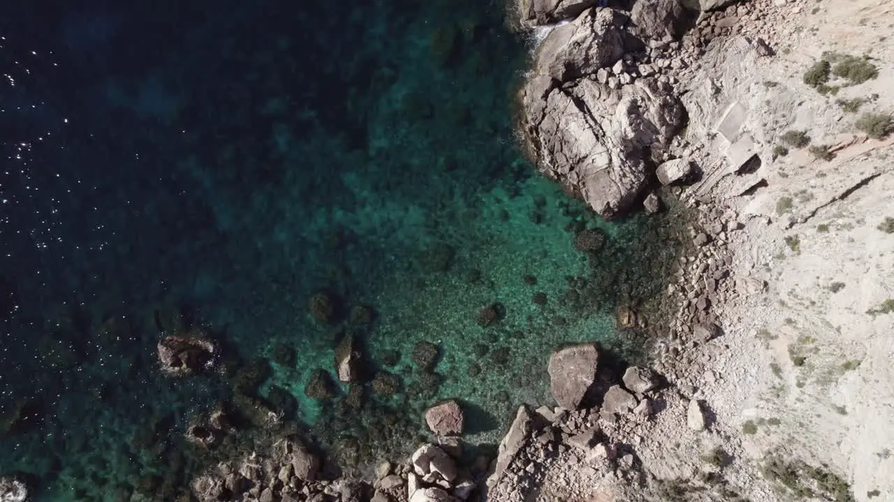 Top down birds eye view drone shot rocks and cliff with ocean water