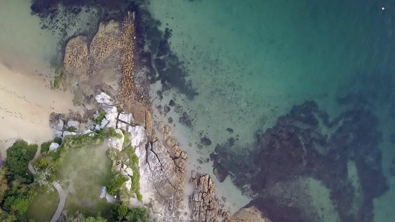 Looking down towards small sandstone rock formation surroundet by cleat blue turquis water