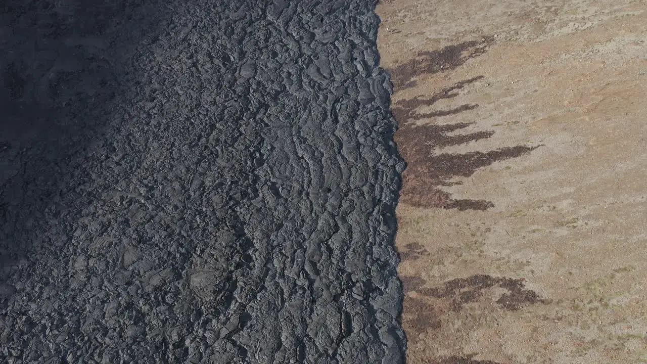 Black solid lava field on slope of valley mountain in Iceland aerial