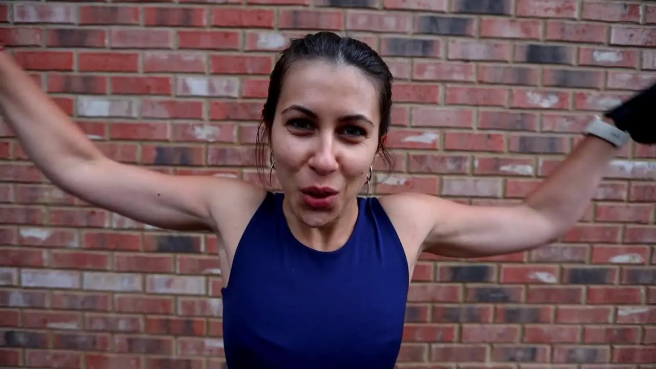 Physically Fit Woman Doing A Dumbbell Exercise Standing Against Red Brick Wall