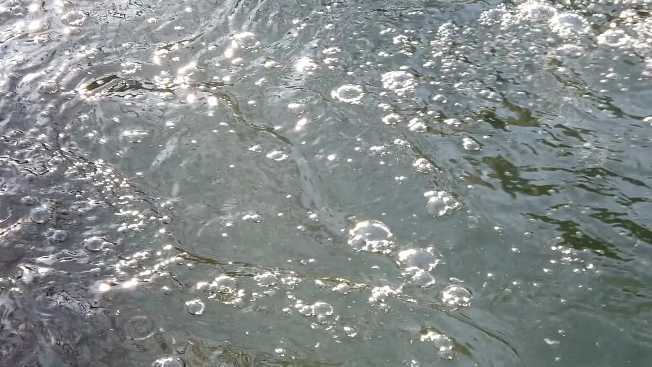 Slow motion of the water between rocks and ice forming bubble and ripple of the surface