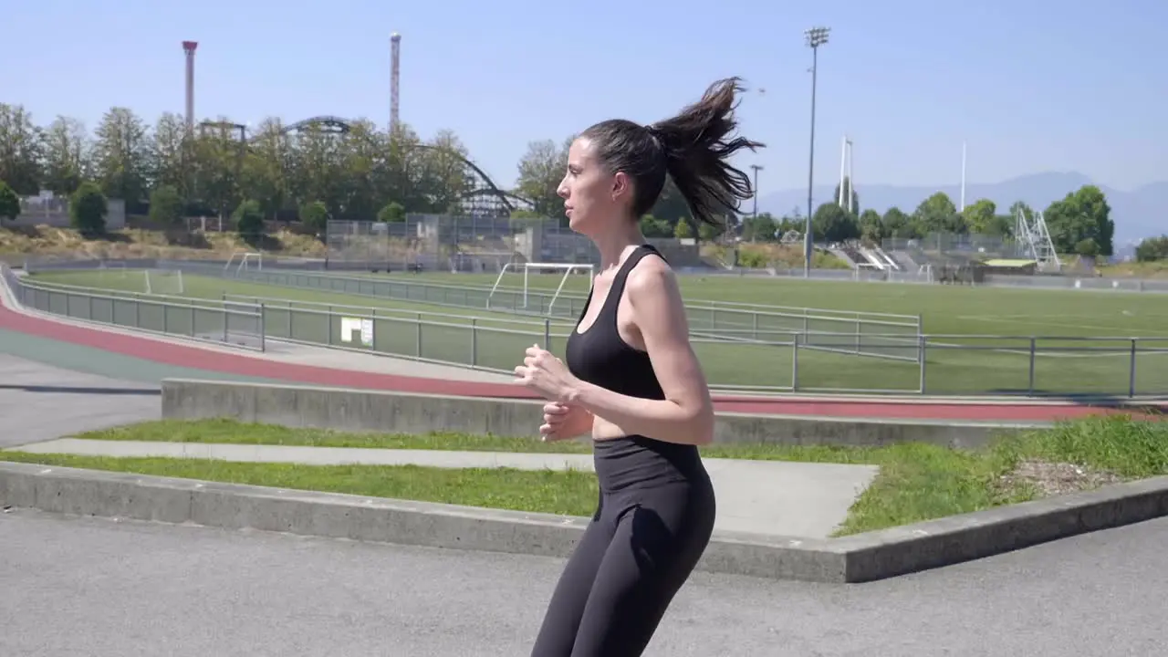 Young Sporty Caucasian Woman Running Around the Sports Field SLOMO