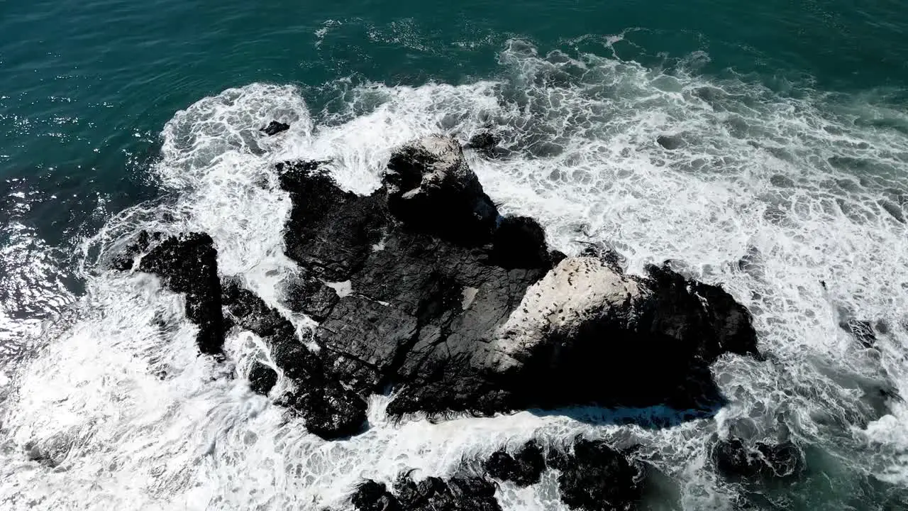 Aerial orbit of Punta de Lobos rocks with birds on their tops on a sunny day