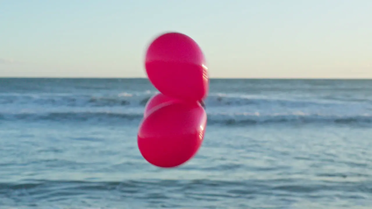 Three red balloons pass by the out of focus sea view