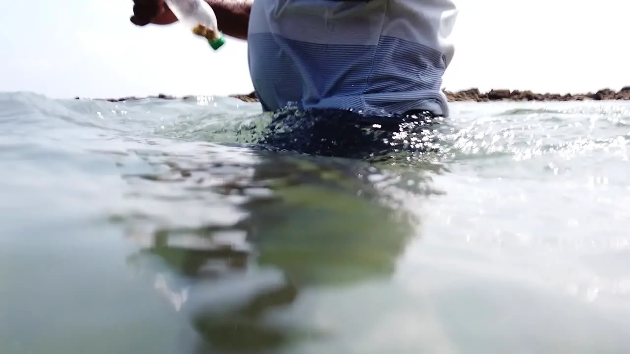 In slow motion the below water and above water view close up of a simple fishing method in the andaman islands using plastic bottles to wind the line around before casting the hook with bait