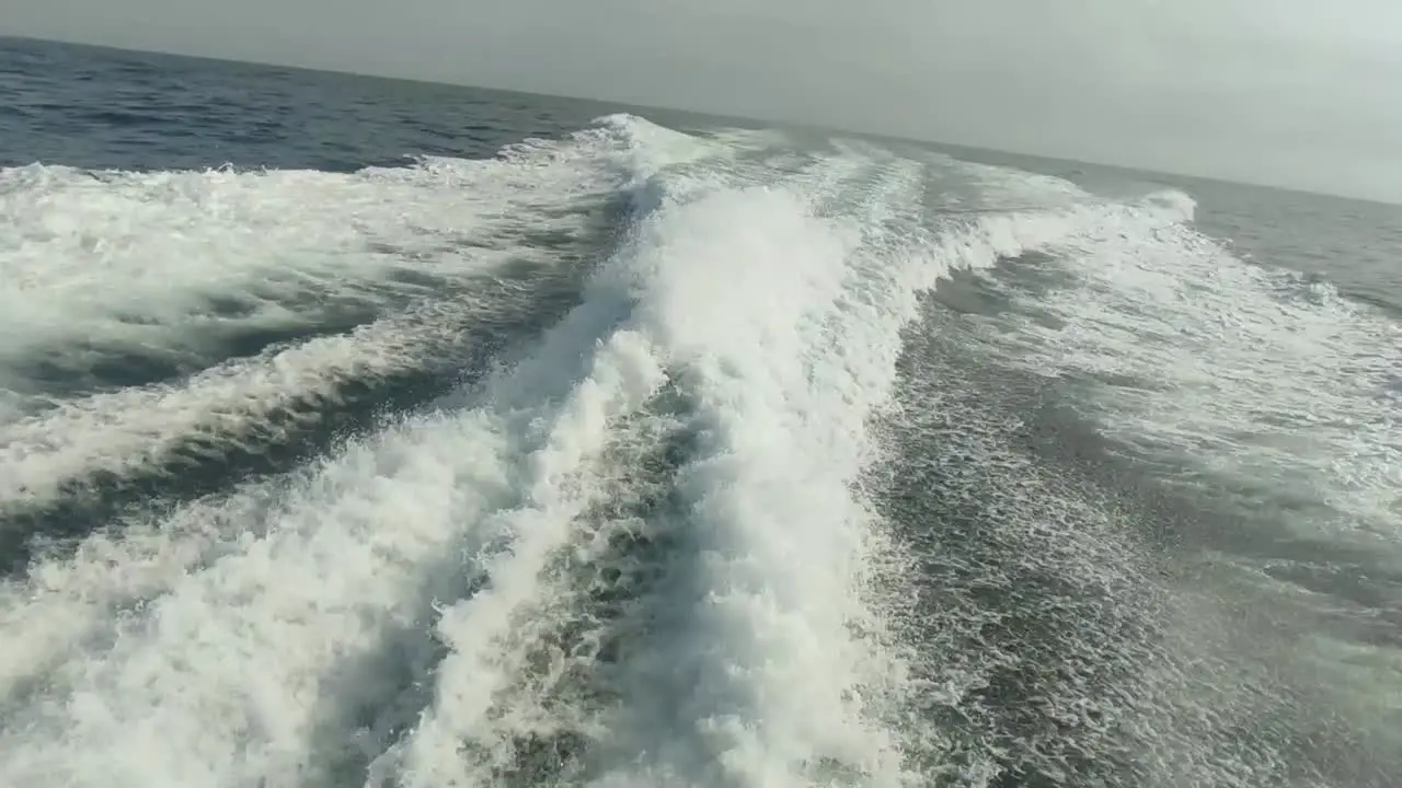 wake of water seen from behind of fast moving motor boat in a clear sky day Blue sea  water surface