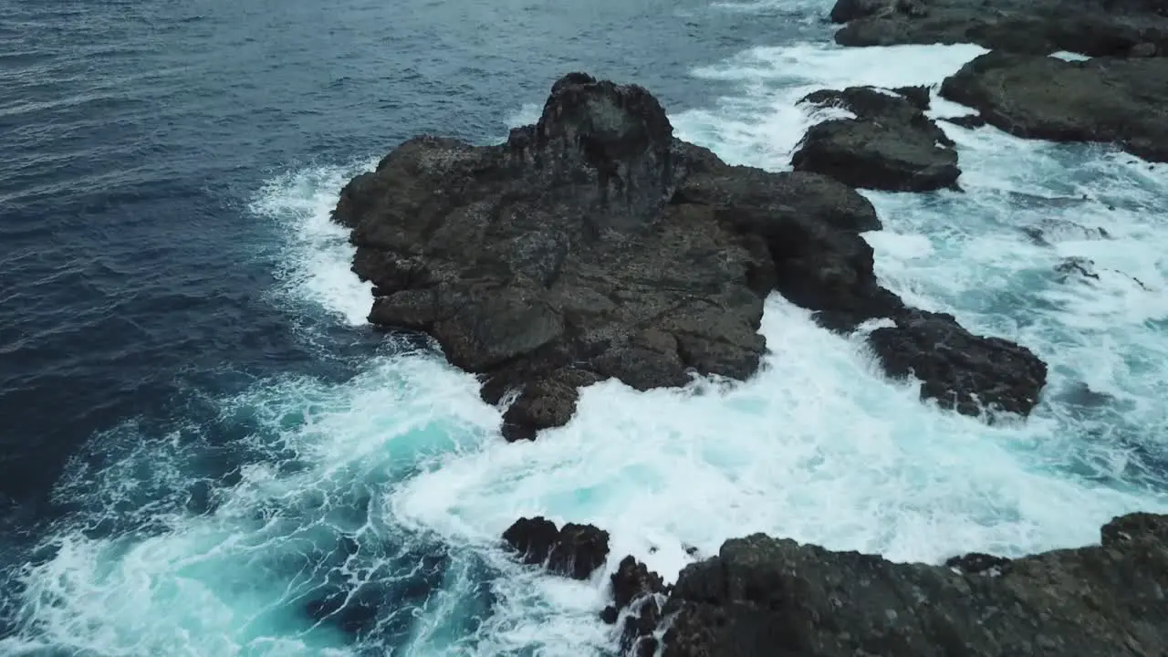 AERIAL 4K Flyover Large Rocks on Edge of Ocean with Waves Crashing Indonesia