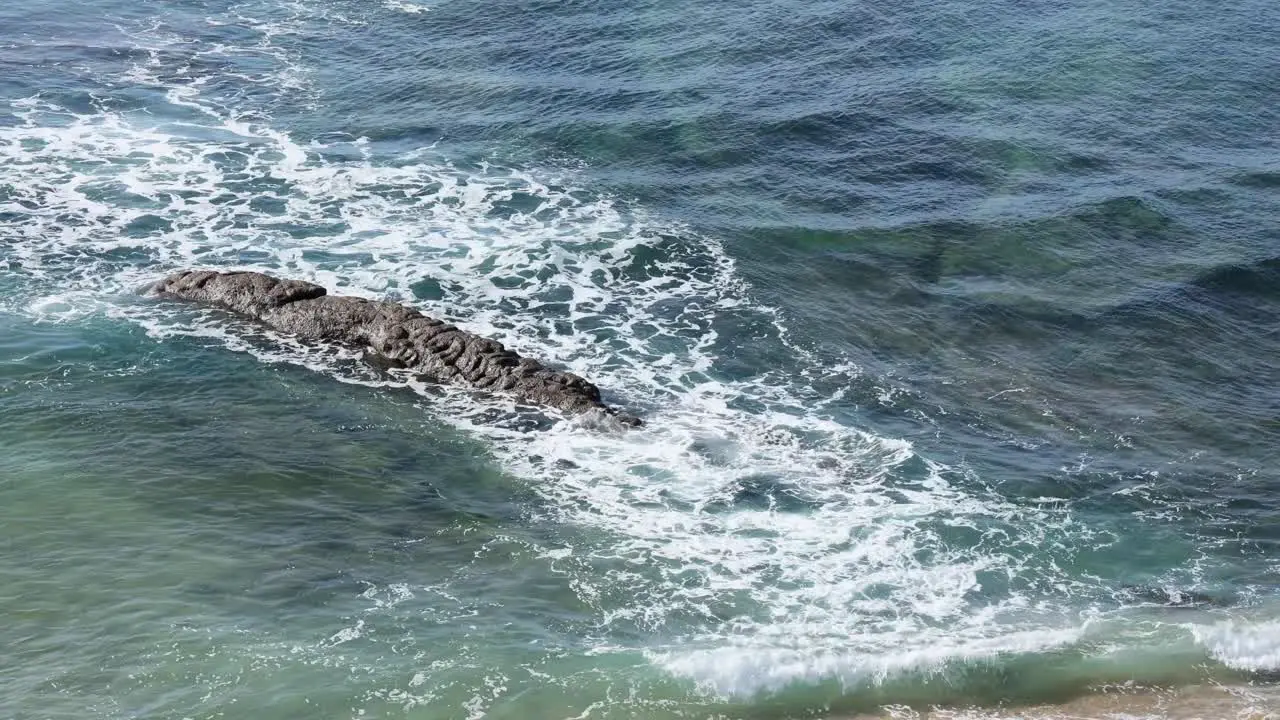 small waves crashing on some rocks in beach of Poça in Estoril