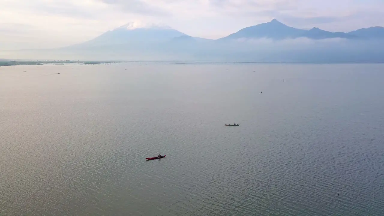 Orbit drone shot of traditional wooden boat on the huge lake with mountain on the background Rawa Pening Lake Indonesia