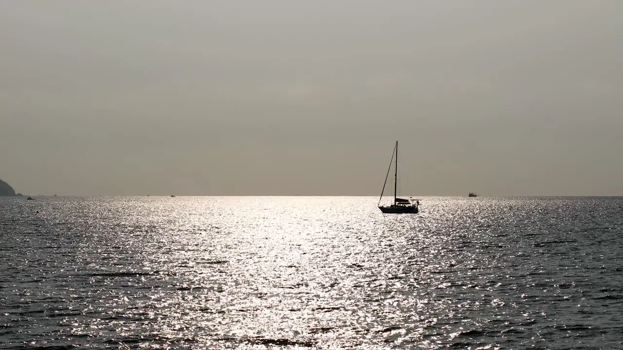 An Isolated Yacht on the Horizon with Sunlight Reflecting on the Calm Waters off the Coast of Bangsaray near Pattaya Thailand