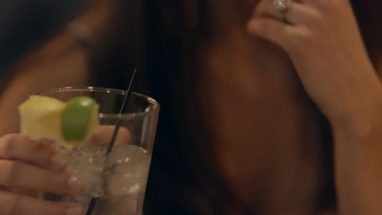 Closeup of pretty party girl holding a cocktail and laughing as she talks to friends