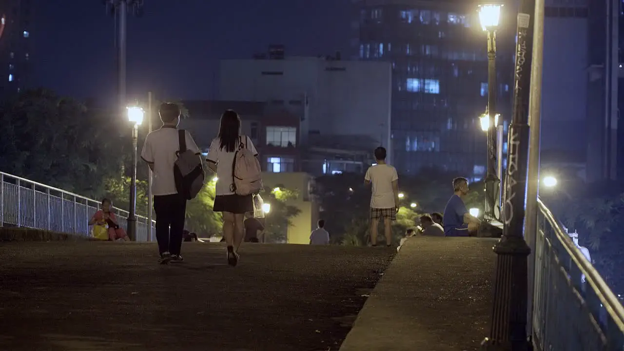 Student Couple in Uniform Walking on a Bridge at Night