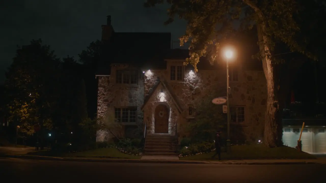 Adult Walking Past House Dark Lit By Orange Street Light In Montreal At Night