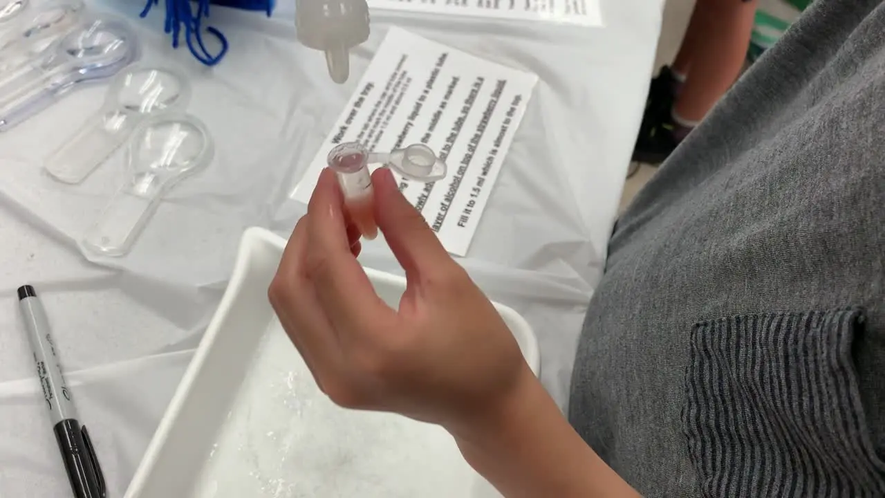 Slow motion video of a young boy dropping alcohol into a small vile to extract strawberry DNA