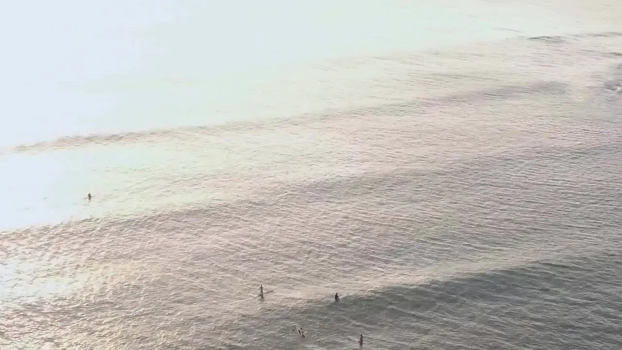 Drone aerial surfers bouncing on waves sunset Hawaii