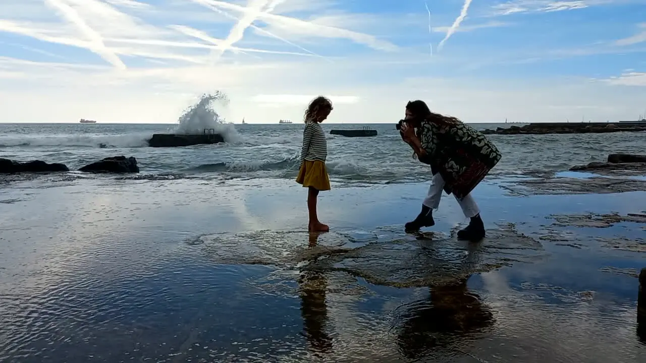 Mother takes photo of her little daughter by the rough sea