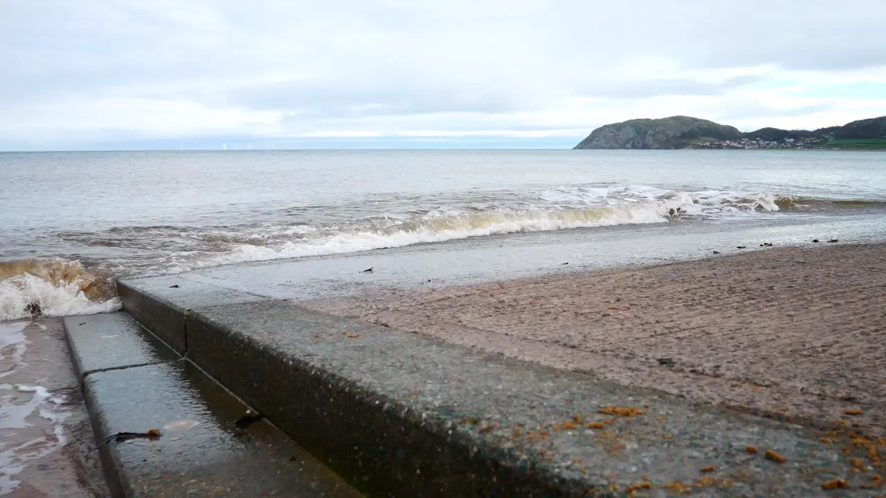 Waves washing against concrete boat landing steps leading to ocean water dolly right shot