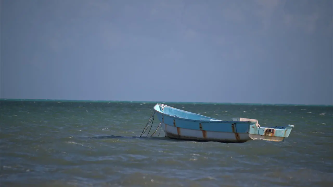 Slow motion of an old rusty fishing boat rocking with the rhythm of the waves in the ocean on a calm sunny day