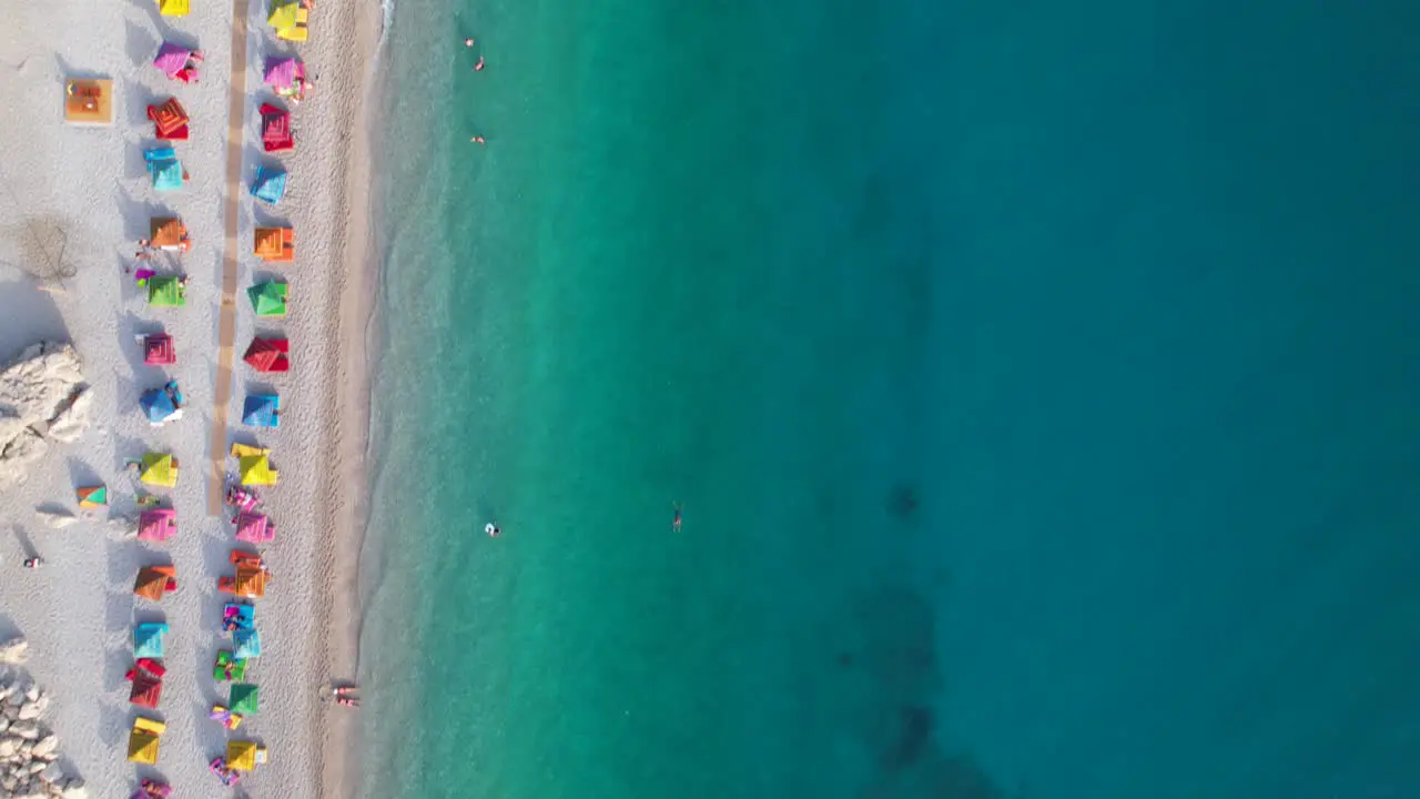 Beach with colorful umbrellas near clean turquoise sea water of Mediterranean summer vacation