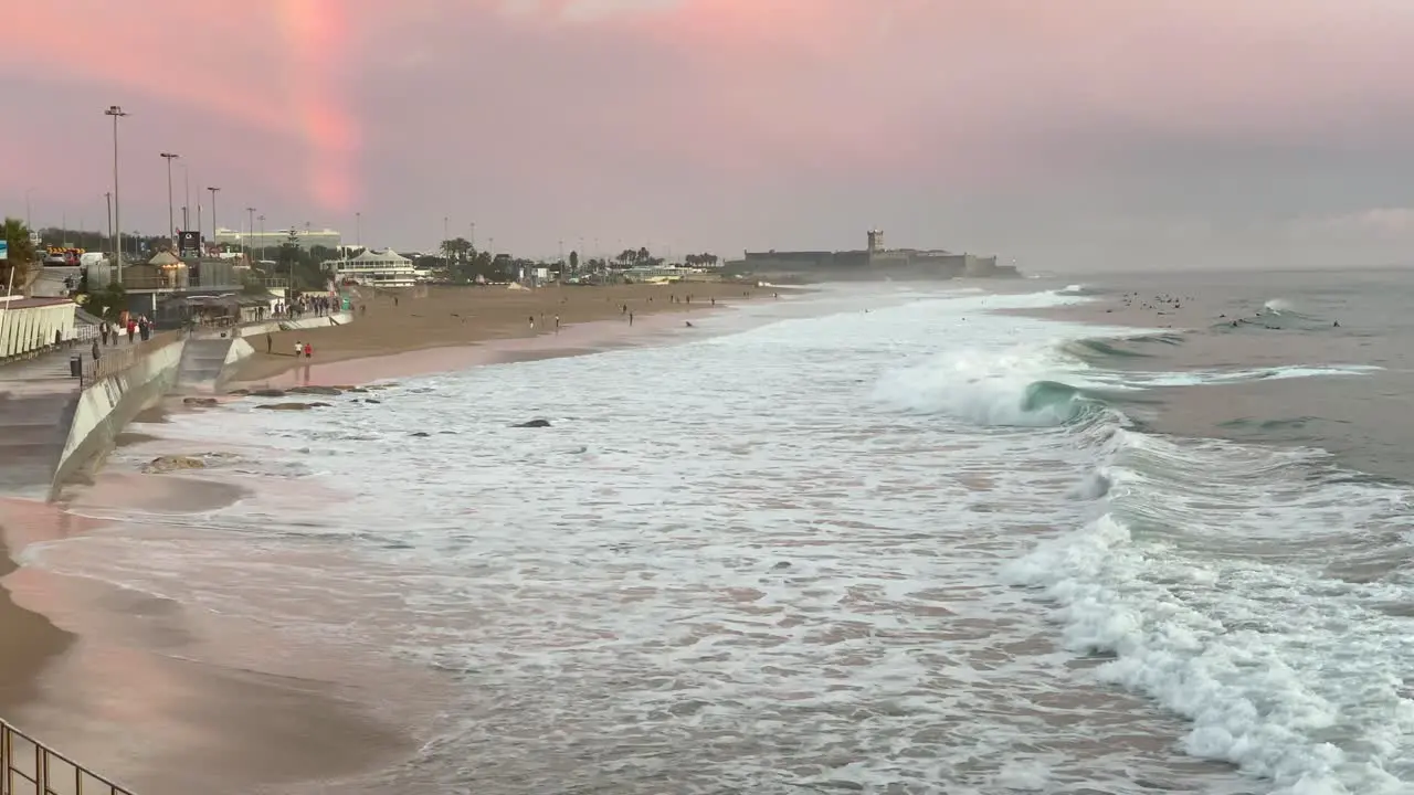 Incredible beautiful sunset sky reflections of Atlantic ocean waves at Carcavelos beach near Lisbon amazing orange teal and blue tones some people walking