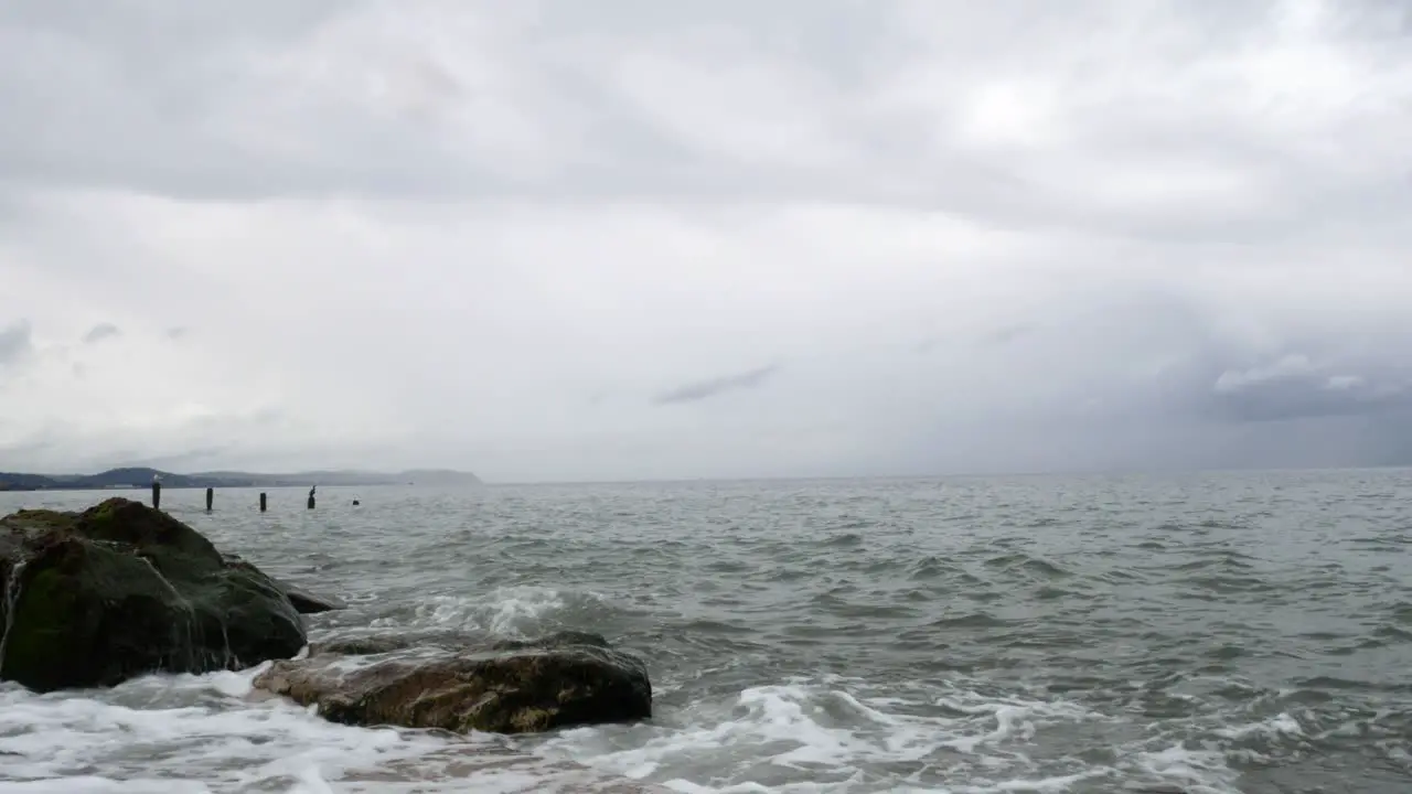 Powerful splashing ocean tide waves breaking wild overcast coastal rocky shoreline closeup