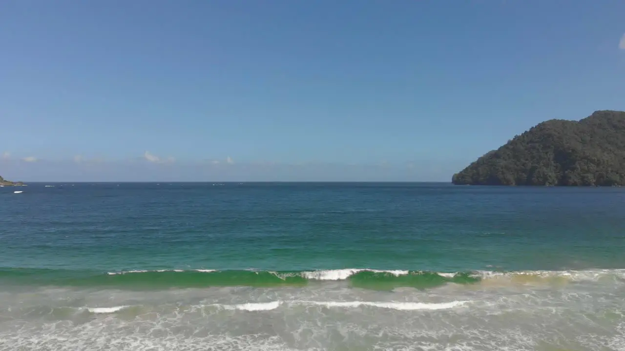 Ascending drone footage of waves crashing at the shoreline the revealing a north coast bay