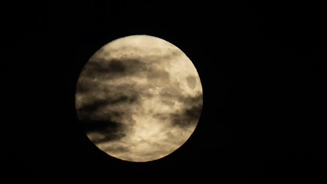 The full moon crosses the night sky behind eerie dark clouds