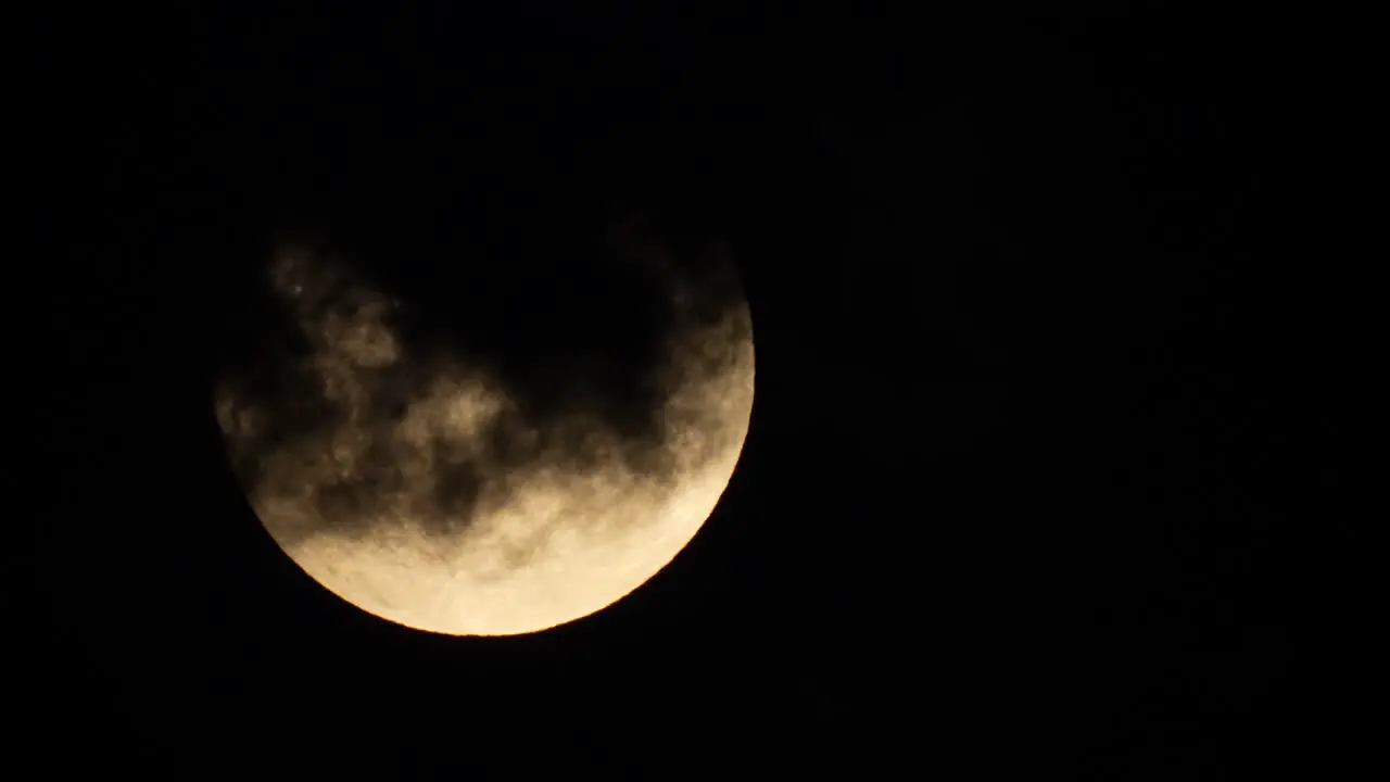 The full moon appears from behind some inky black clouds