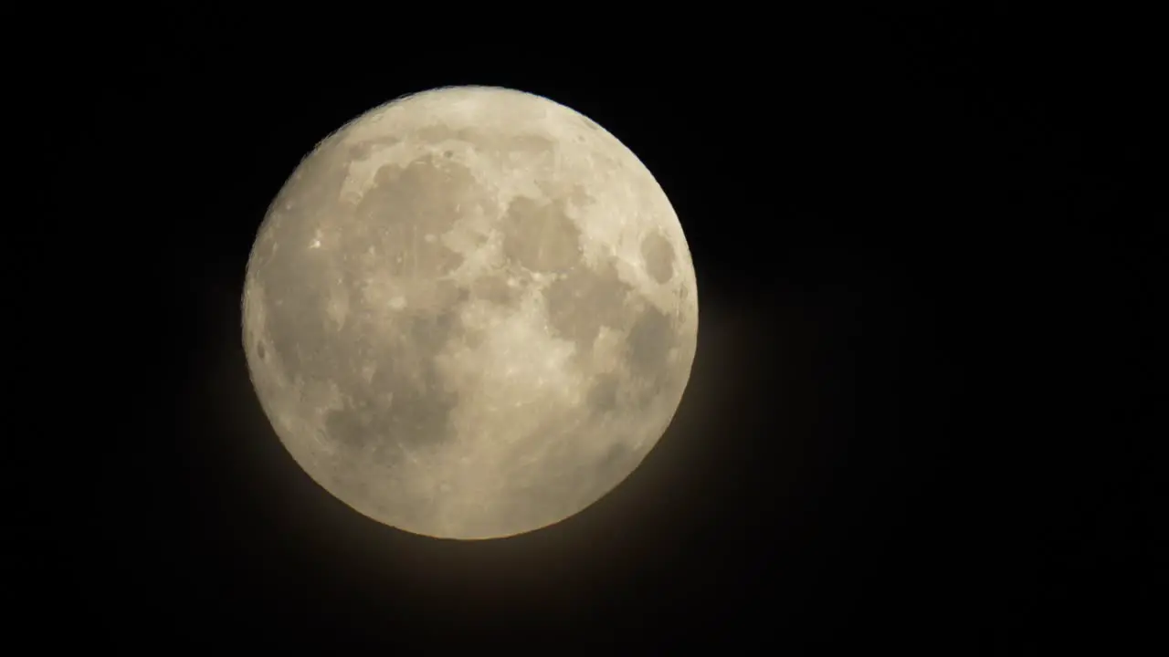 Wisps of thin cloud cross the face of the rising full moon