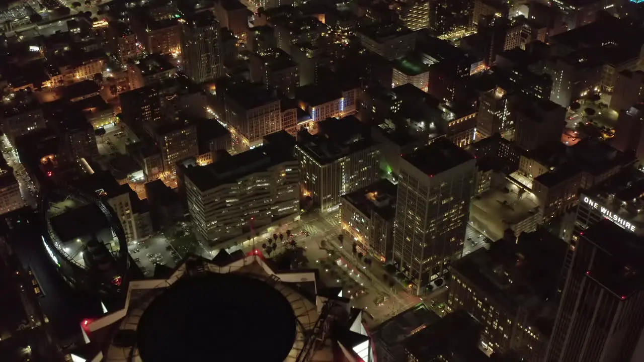 US Bank Tower Rooftop Helicopter landing pad in Los Angeles Skyline at Night Aerial Tilt down revealing lit up glowing Cityscape at Dusk Circa 2019