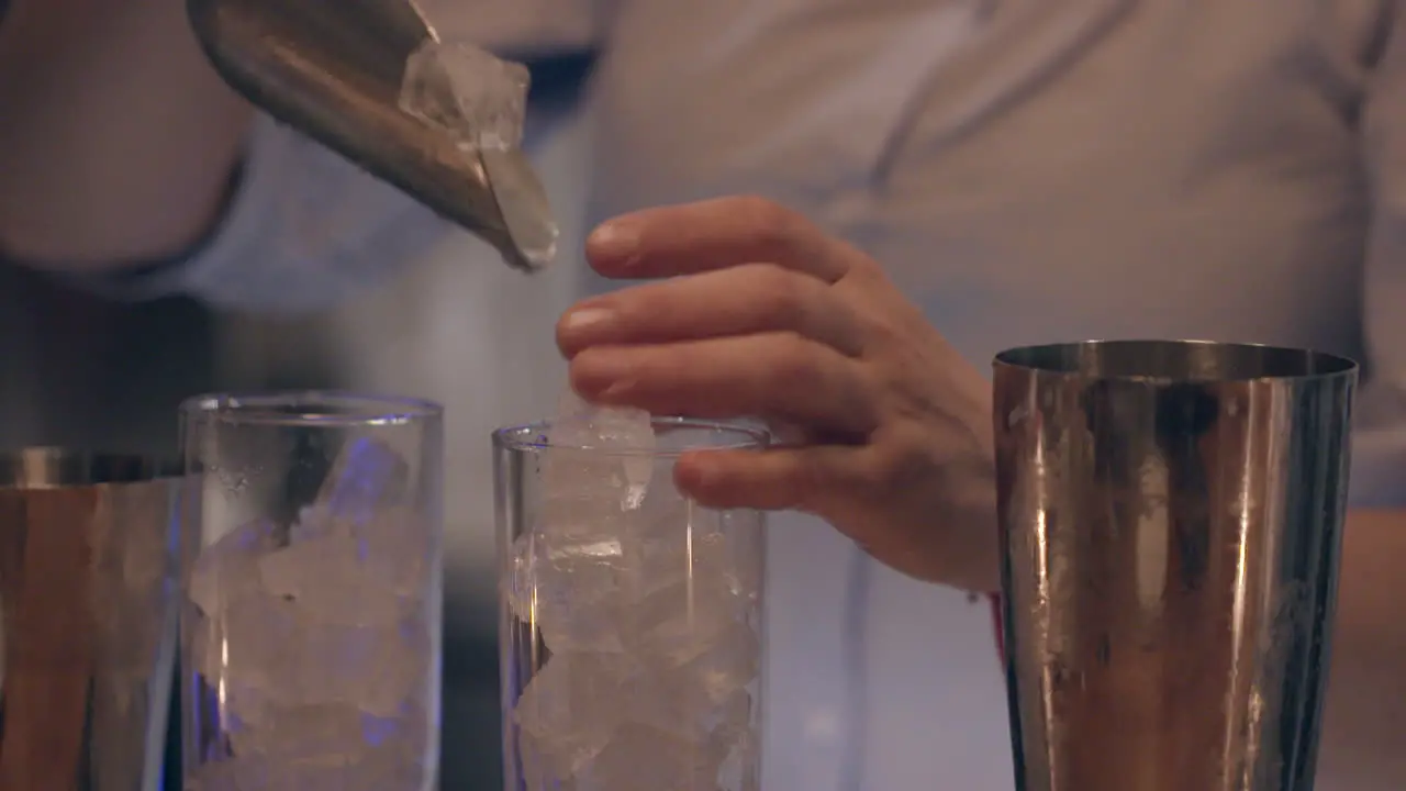 bartender fills two tall glasses with ice