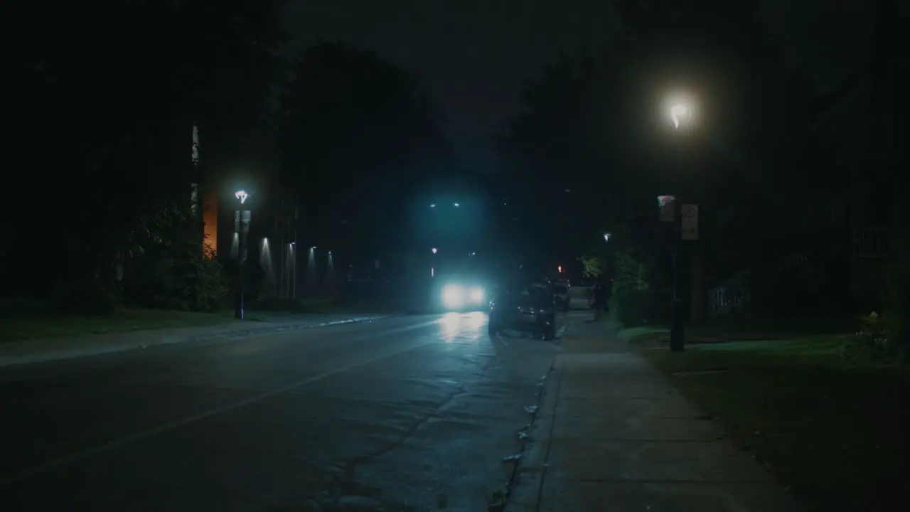 Dark Lit Suburban Street With Car With Headlights On Going Past