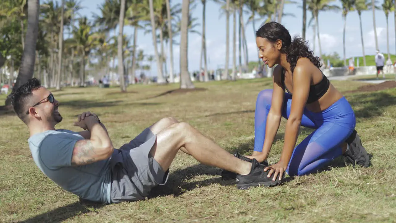 Woman helping man with exercise in park