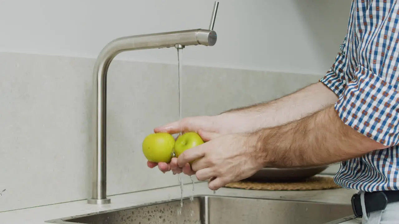 Cerca De Las Manos Del Hombre Lavando Dos Manzanas Verdes En Un Fregadero De Cocina Moderno